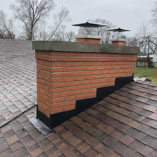 Brick chimney with new black flashing, crown and stainless steel chimney caps