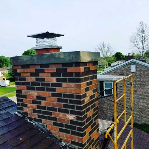 multi-colored chimney masonry with new crown and chimney cap