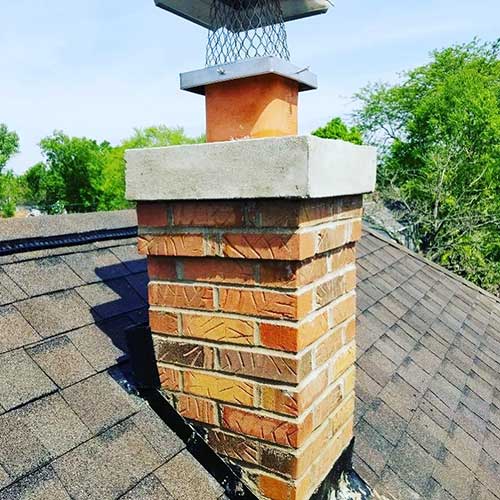 Brick chimney with newly rebuilt chimney crown and new stainless steel chimney cap with screen