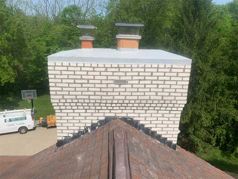 White chimney masonry restored, new crown and stainless steel chimney caps after Complete Grindout and Retuckpoint