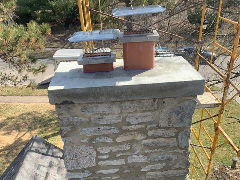 Restored stone chimney masonry, newly poured Concrete Crown and new stainless steel Chimney Caps After rebuild