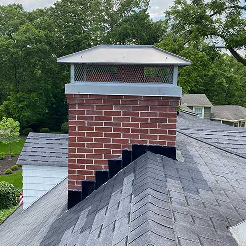 Red brick masonry chimney with custom-fitted triple flue stainless steel chimney cap