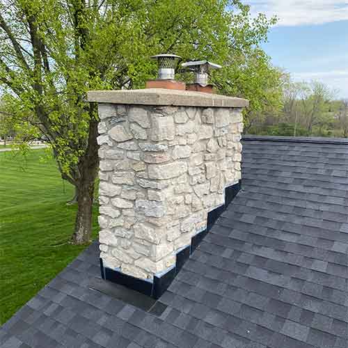 White stone chimney masonry with new crown and stainless steel chimney caps