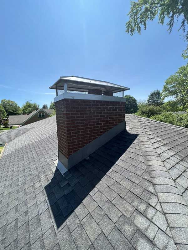 Brick chimney after rebuild with restored and repaired masonry, new stainless steel chase cover and cap