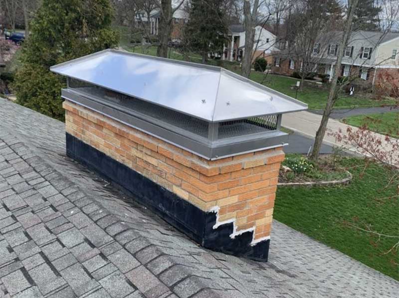 Restored chimney masonry free of stains, newly poured crown, and new stainless steel chase cover with custom-fitted chimney cap
