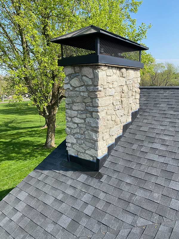 Mid-Valley Chimney - Request Appointment - image has a stone fireplace with black cap and tree in the background.