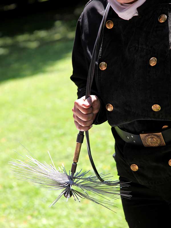 Original of Chimney Sweep with gold buttons going down each side of the shirt and a golden belt buckle.  He is holding a sweep brush.