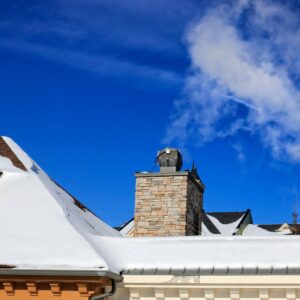 a chimney with smoke coming out on a snowy roof