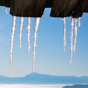 icicles hanging off a roof when a snowy mountain landscape in the background