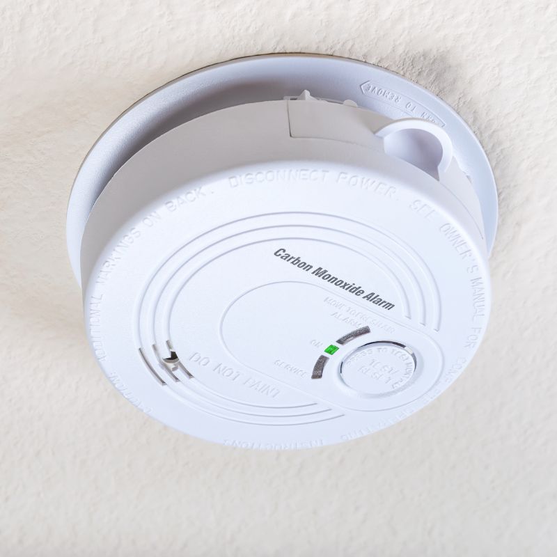a white round carbon monoxide detector on a ceiling